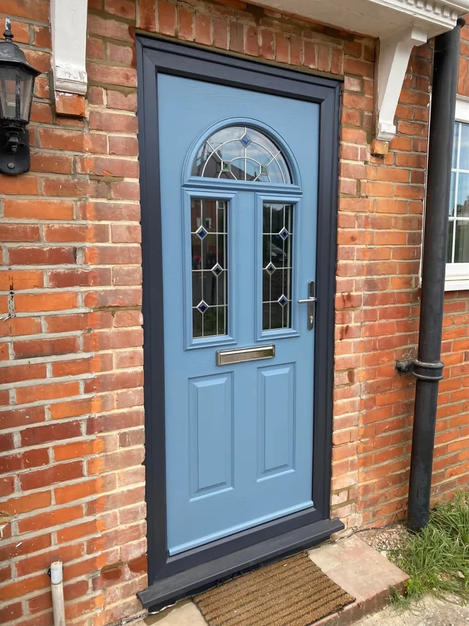 After: the same doorway with a pale blue door, leaded glass panels and a dark grey frame