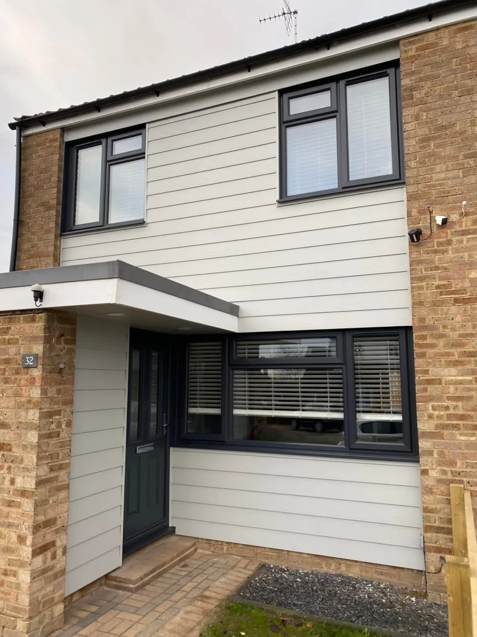 After: the same house front with dark grey windows, a dark grey door and pale cladding