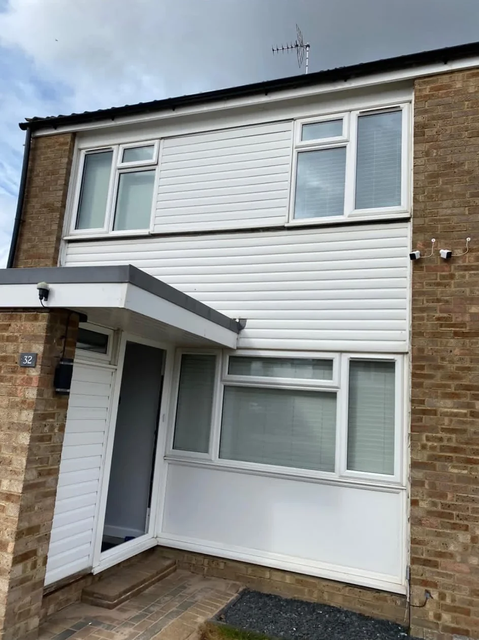 Before: a house front with white window frames, white cladding and a white entrance door